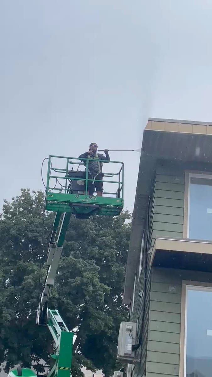 Pressure washing residential exterior from scissor lift in Vernon BC